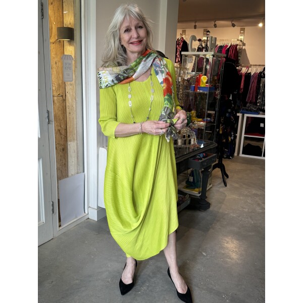 Thanny Asymmetric Plisse Midi Dress in Lime Green has a draping back and front and is made from a stretch plisse fabric. Worn with Desigual Newspaper Scarf.