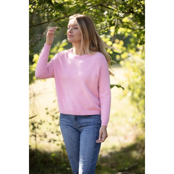 Woman wearing a super soft pink cashmere-feel jumper with dropped shoulders